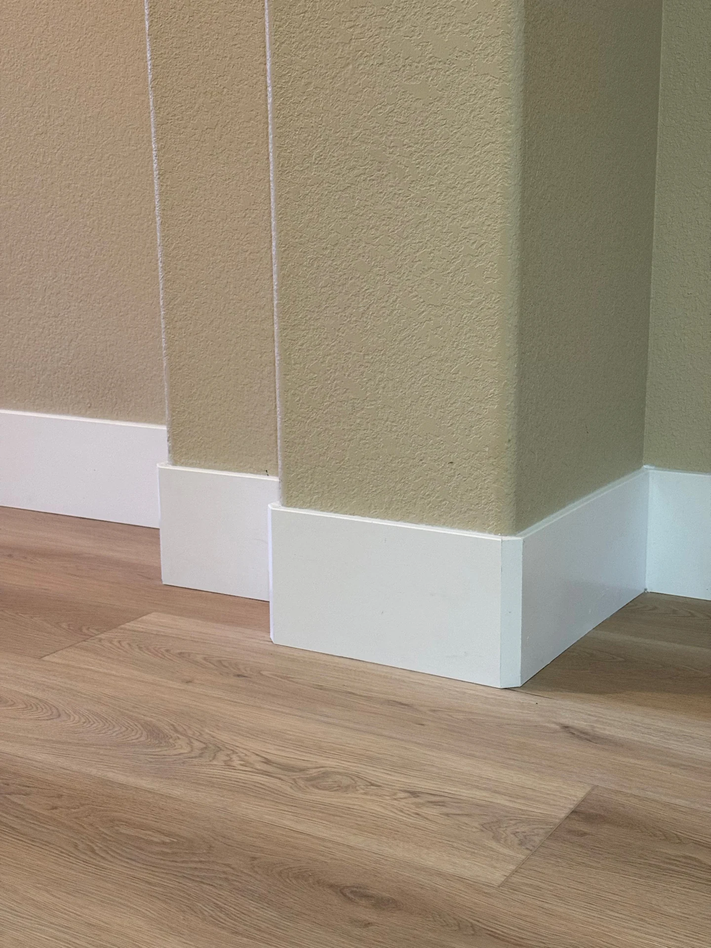 Close up of new plank flooring meeting crisp white baseboards at an outside corner