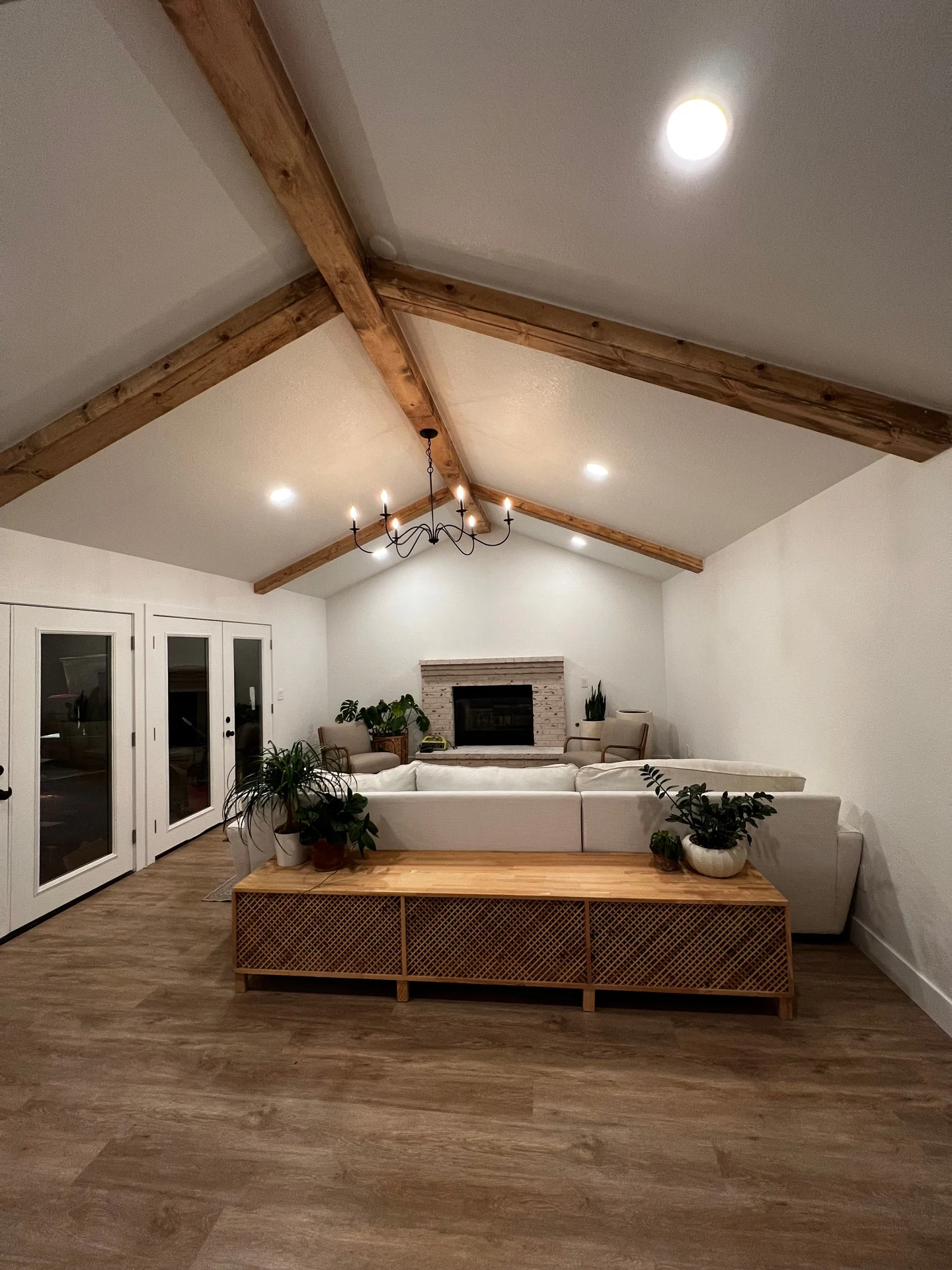 Living room under a vaulted ceiling with exposed wood beams and new plank flooring
